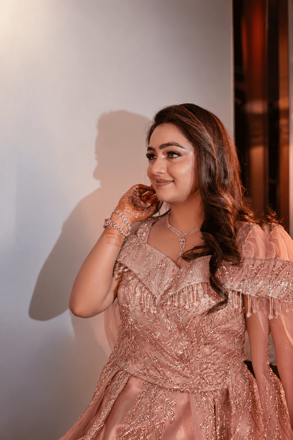 Neha in an ivory and gold lehenga beside an arched palace window